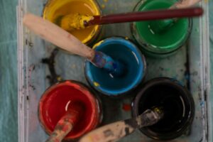 Pots de peinture colorés avec pinceaux, symbolisant une activité d’art-thérapie ou de créativité
