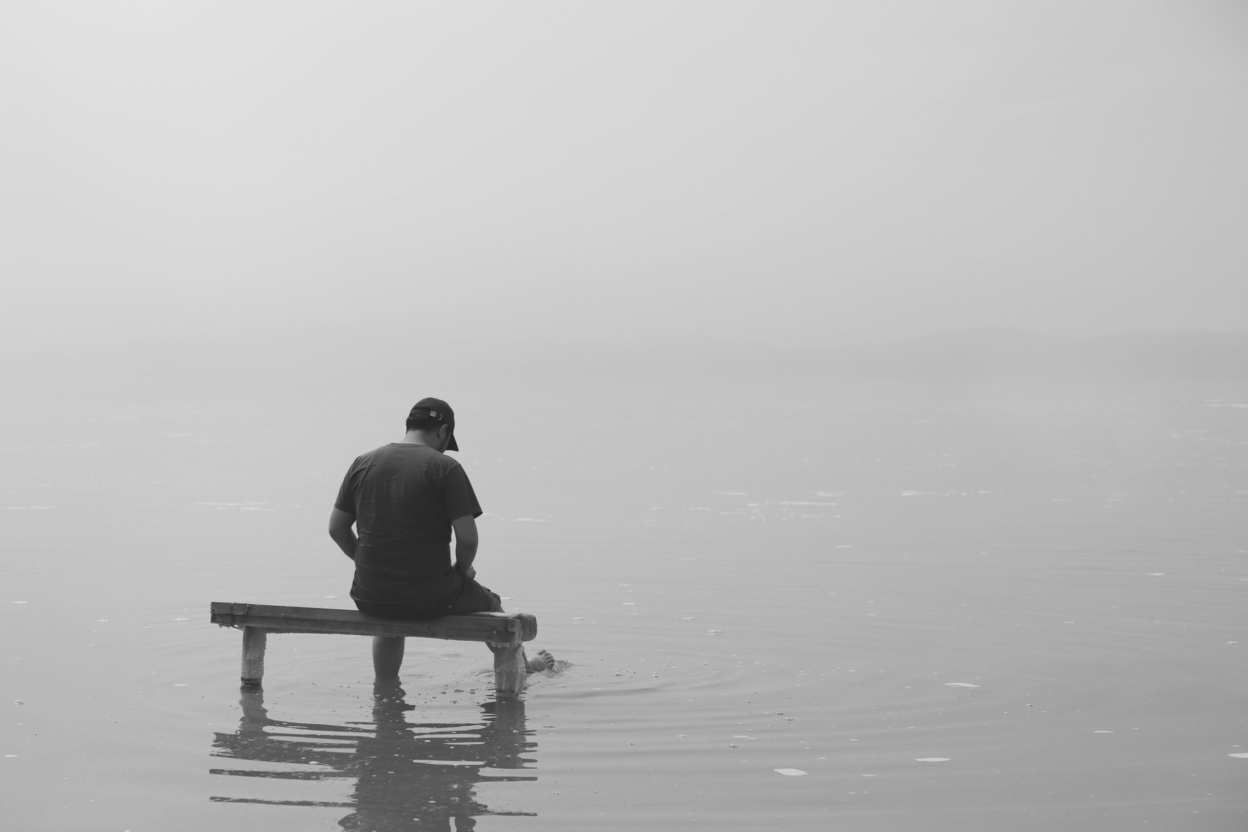 Une personne assise face à la mer, la tête baissée, illustrant la solitude et l'épuisement liés au burn-out
