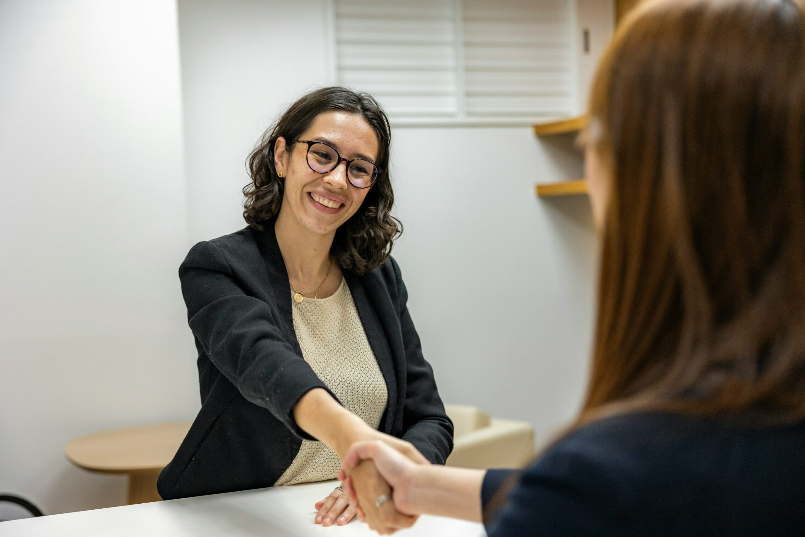 Une femme souriante tend la main lors d’un entretien, illustrant l'accompagnement bienveillant du collectif contre le burn-out